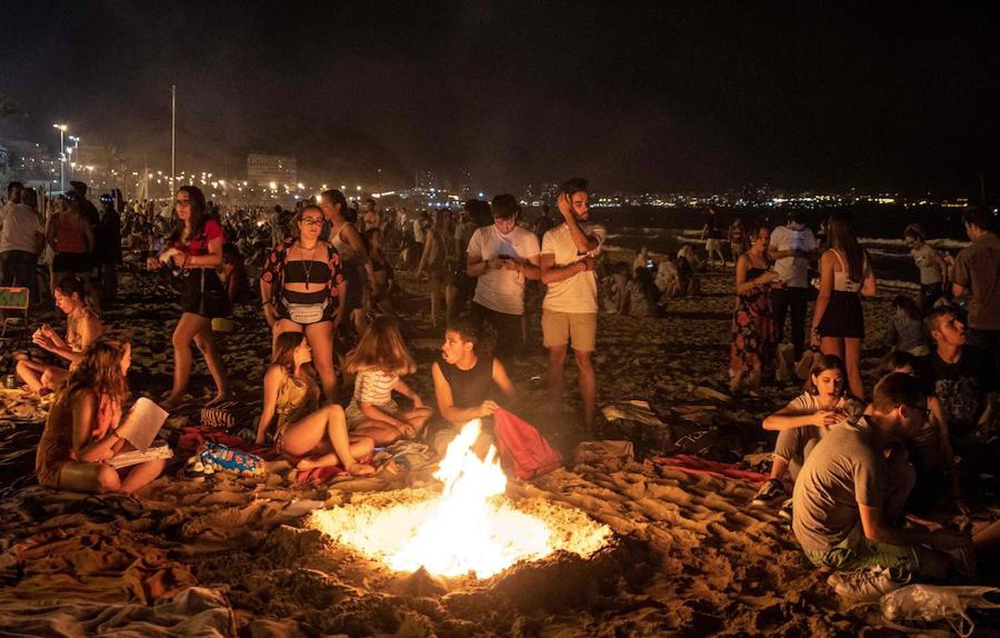 Las personas se reúnen alrededor frente al fuego durante la noche de San Juan en una playa de Alicante, Valencia. 