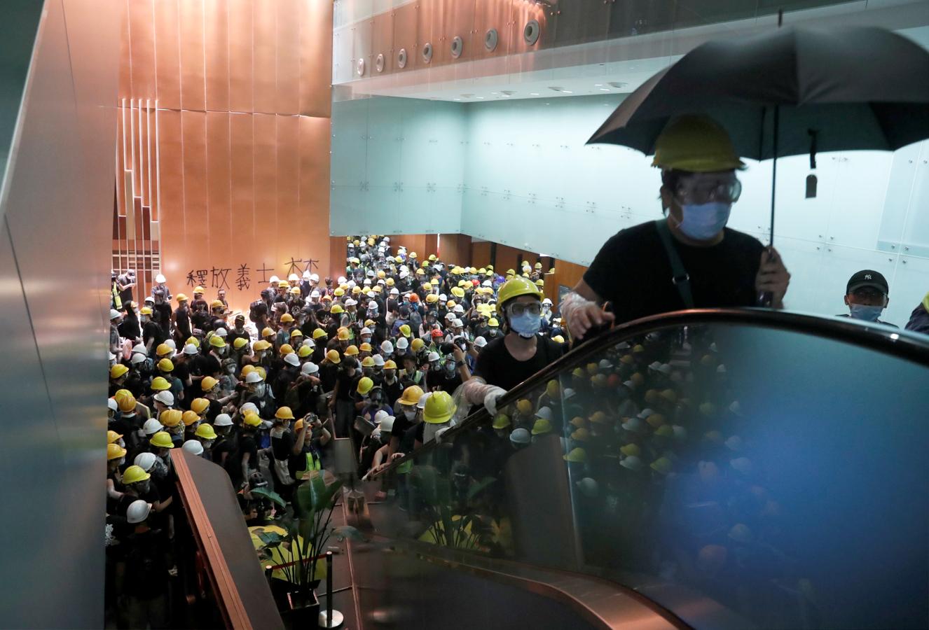 Los manifestantes con cascos de obreros amarillos y blancos suben las escaleras mecánicas que dan paso a la Cámara. 