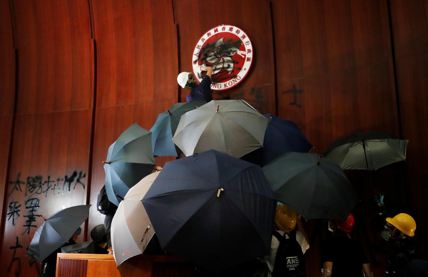 Un manifestante desfigura el emblema de Hong Kong después de que irrumpieran en la sede legislativa. 