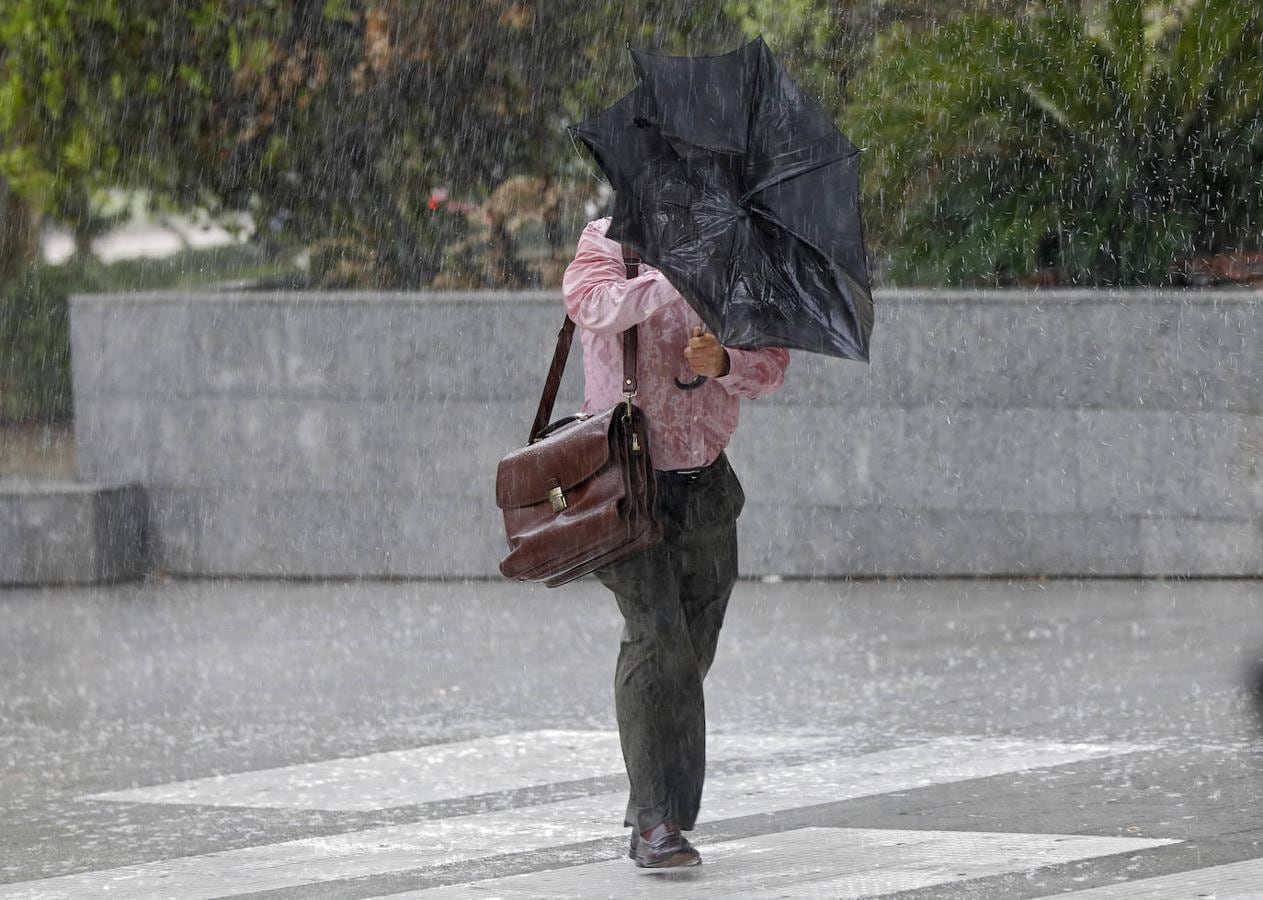 Un hombre intenta resguardarse de la lluvia. 