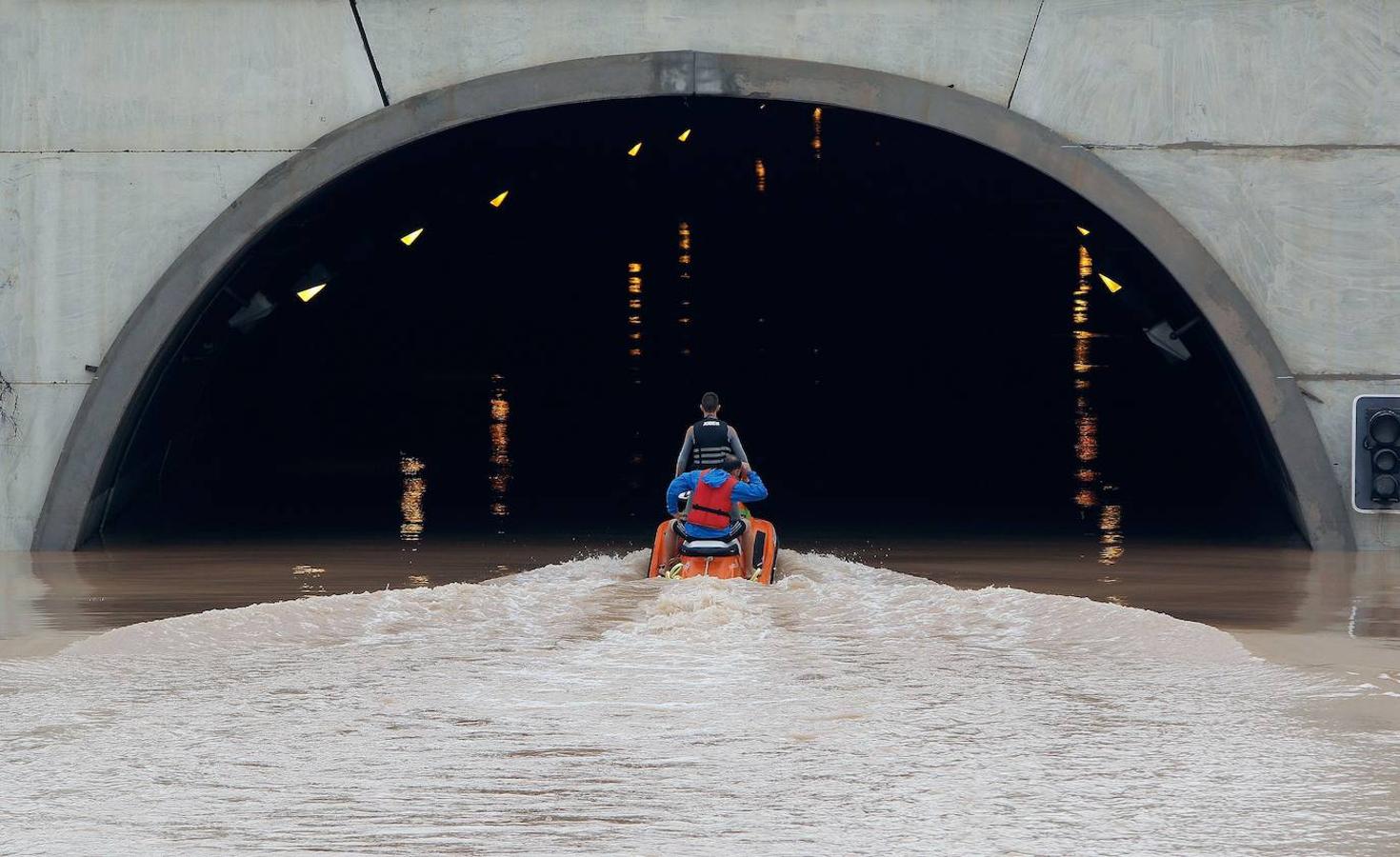 Varios miembros de los servicios de rescate cruzan en moto acuática la salida del túnel de la AP-7 a la altura del municipio alicantino Pilar de la Horadada. 