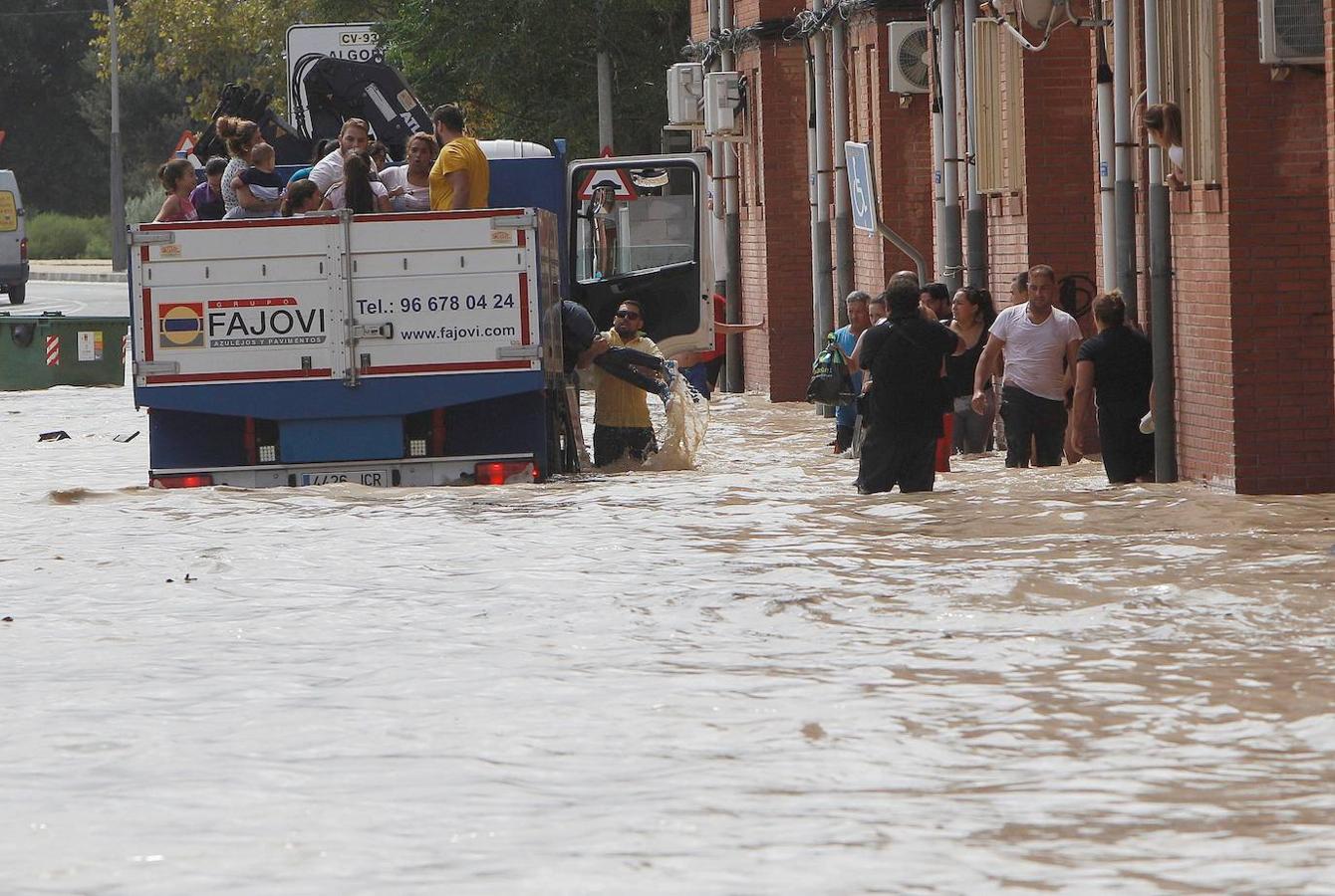 Un camión traslada a varios vecinos de Almoradí este viernes tras la rotura del muro del cauce del río Segura por la crecida del río que ha provocado el desbordamiento a la entrada de la población.. 