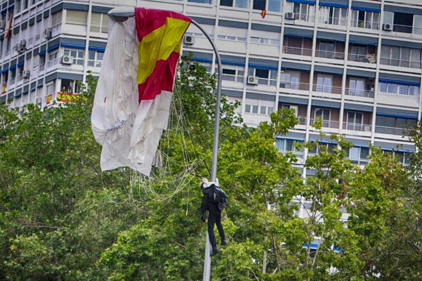 Un paracaidista que descendía con la bandera de España se ha quedado enganchado de una farola durante el desfile. 