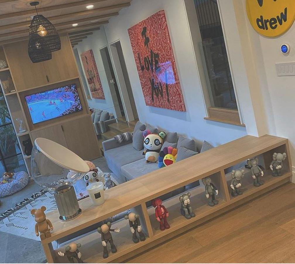 Muebles de diseño. El salón se fotografía desde muchos ángulos. En la imagen se aprecia una estantería con esculturas de KAWS de miles de euros, sobre ella hay una lámpara de diseño
