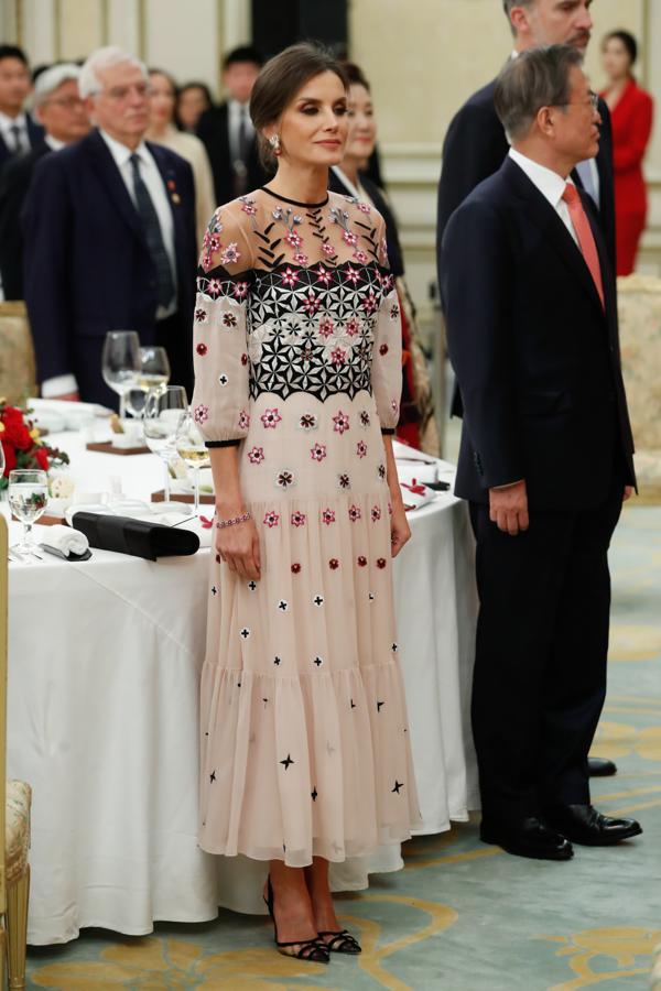 En Seúl, la Reina Letizia triunfó con su vestido más innovador. Fue en la cena oficial ofrecida por el presidente Moon Jae-In y su esposa, Kim Jung-Suk, cuando sorprendió con un romántico diseño con alguna transparencia en la zona de los hombros. De cuello redondo, media manga, cuerpo entallado y falda de vuelo, además de delicados bordados de flores. La prenda pertenece a la marca británica Temperley London, habitual en los armarios de Catalina de Cambridge y rostros conocidos del panorama nacional como Blanca Suárez y Paula Echevarría.. 
