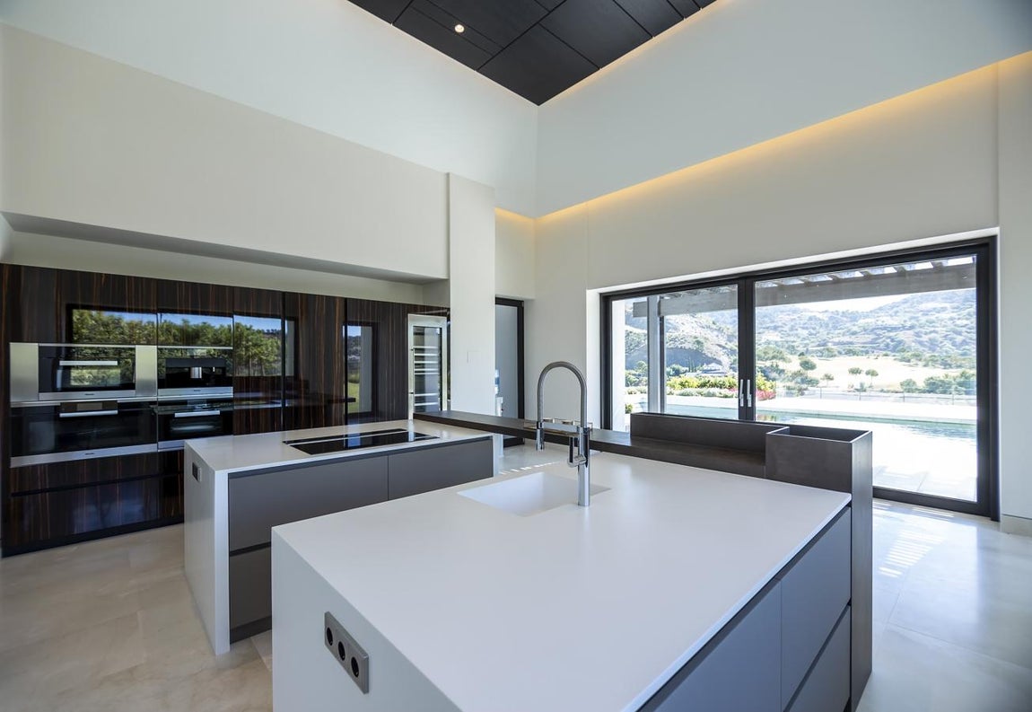 Villa Capriccio: 13,5 millones de euros. Levantada justo frente al campo de golf, esta moderna vivienda disfruta de increíbles vistas al golf, al campo y a las montañas. Sus techos altos y grandes ventanales hacen de su gran salón un espacio muy luminoso y cálido, una triple estancia distribuida en sala de estar principal con chimenea, comedor y espacio de estar familiar. Junto al salón se encuentra la cocina gourmet de planta abierta totalmente equipada, con barra de desayuno, una sala de estar familiar y con acceso directo a las terrazas y al exuberante jardín, que incluye un putting green privado