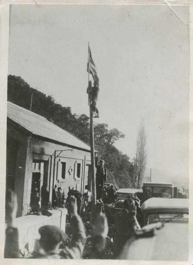 Soldado del cuerpo del Ejército de Navarra iza la bandera nacional en un poste de telégrafos de Le Perthus, poco después de llegar las tropas nacionales a dicha población francesa. 