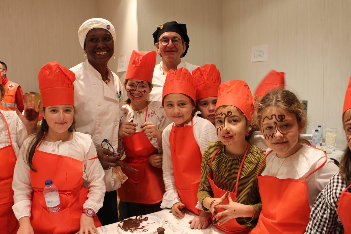 El chef Juan León con su ayudante Esther Richardson y un grupo de niñas participando en el taller de chocolate