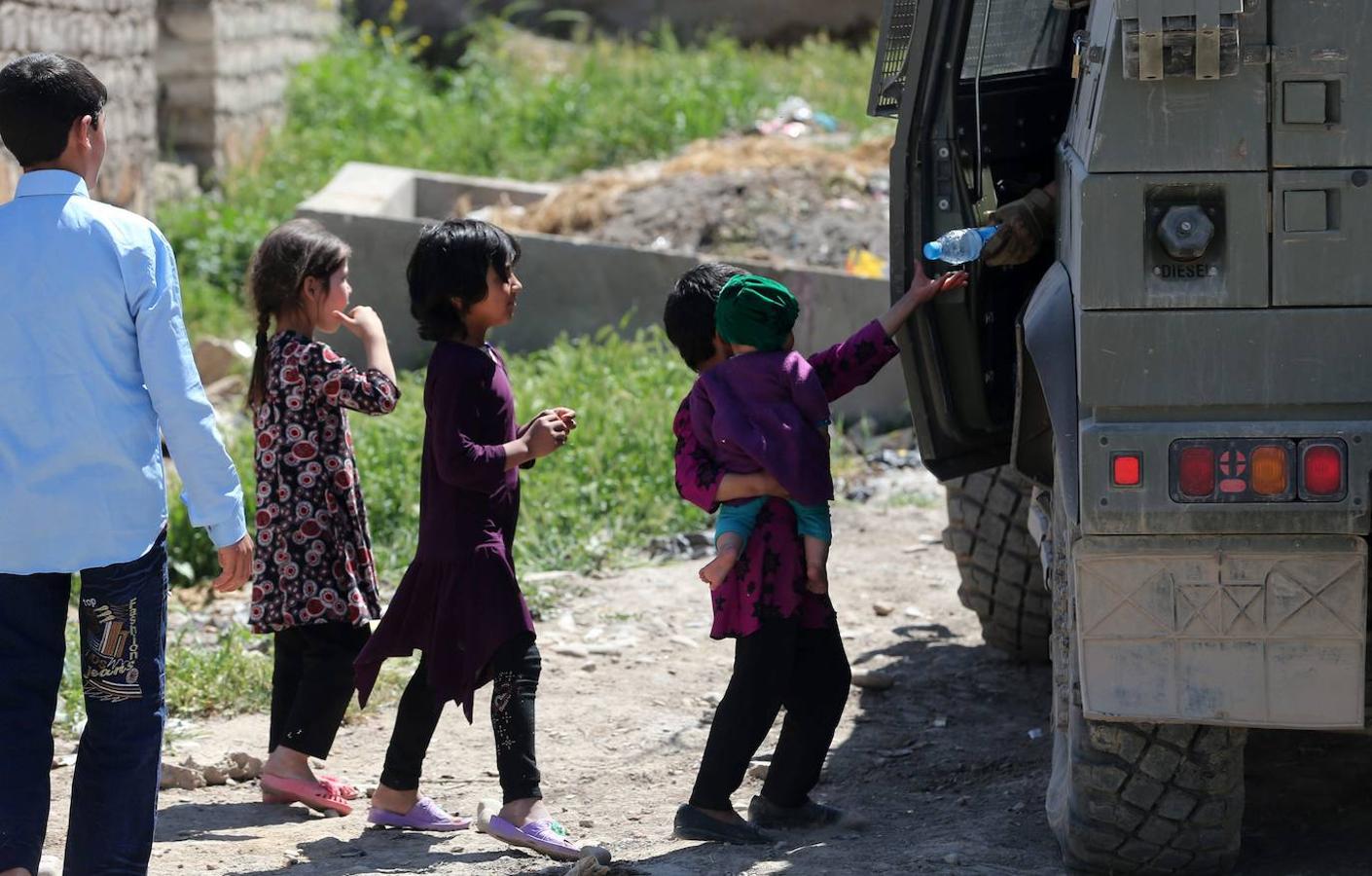 Un soldado reparte agua a unos niños. 