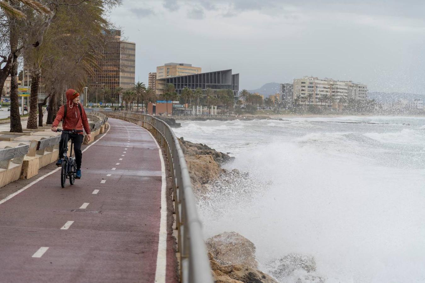 Un ciclista circula junto a la costa con fuerte oleaje en Palma de Mallorca, este lunes. La borrasca Karine, que mantiene este lunes en alerta a casi toda España por rachas de viento de hasta 120 kilómetros por hora, "amainará bastante" a partir de mañana.. 