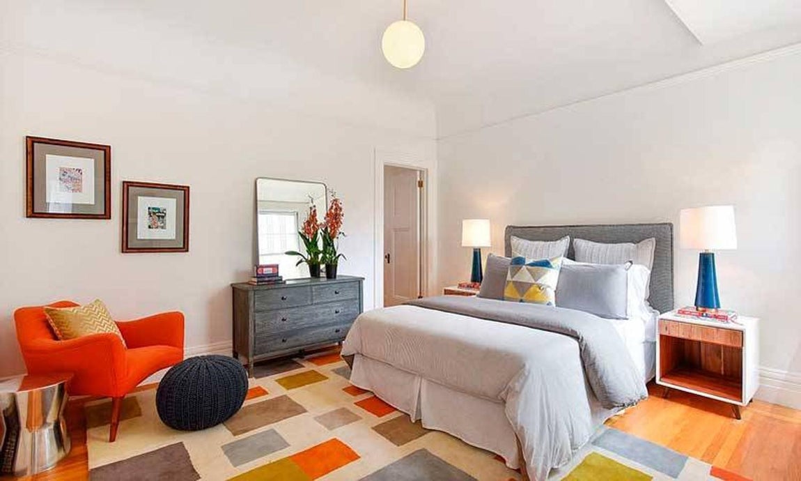 Así es la nueva casa de Julia Roberts en San Franciso. Cada uno de los dormitorios cuenta con un diseño totalmente diferente. Así, encontramos esta colorida habitación con un tinte más moderno que la habitación principal, con una butaca naranja, lámparas con pies en azul y una alfombra multicolor.