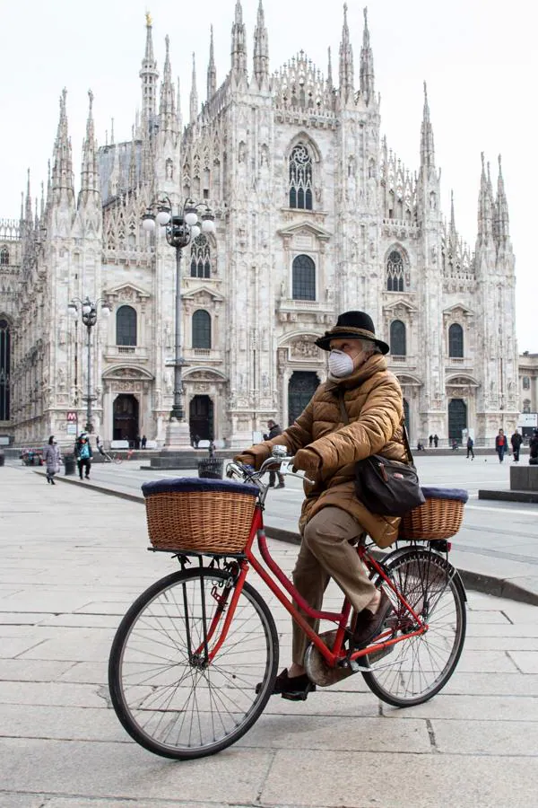 Milán. Una ciclista pasea frente al Duomo de Milán en una plaza con un puñado de turistas