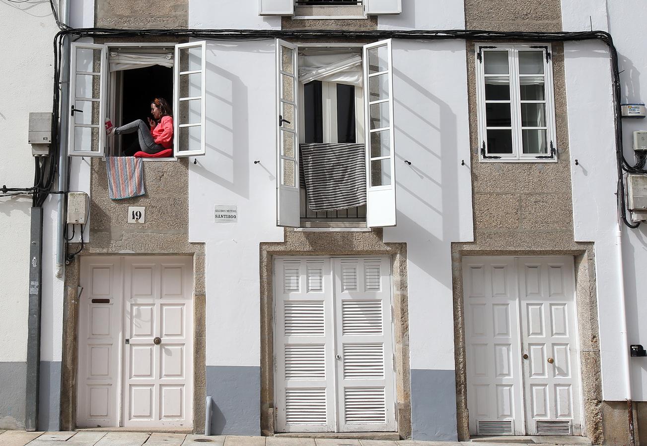 Una mujer pasa la cuarentena sentada en la ventana en una calle de la capital gallega.. 