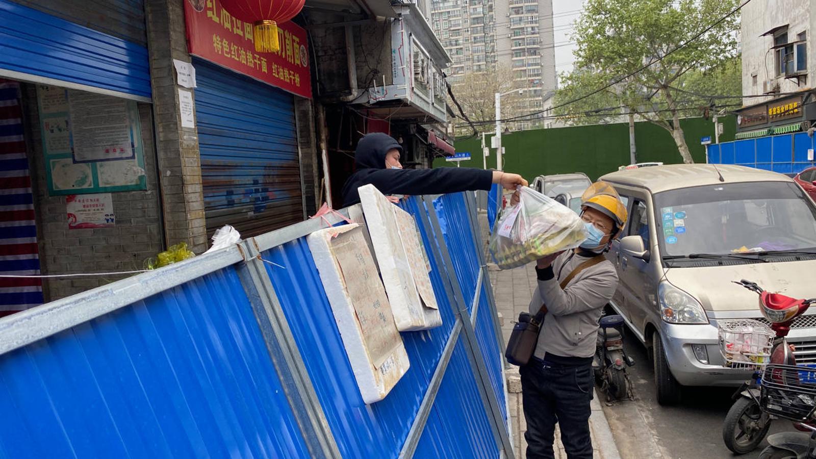 Algunas tiendas y puestos de comida de Wuhan están separados de los clientes por vallas para guardar el distanciamiento social. 