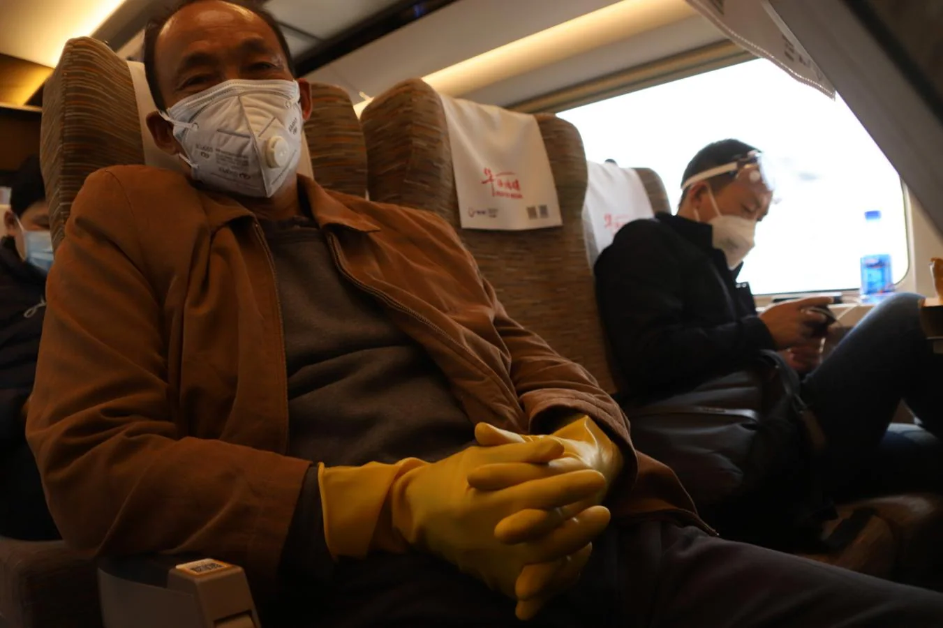 Junto con su máscara, obligatoria en China, un pasajero se cubre las manos con guantes de látex para no tocar nada en el trayecto en tren de Wuhan a Pekín, ya que el virus puede permanecer en algunas superficies durante varios días. 