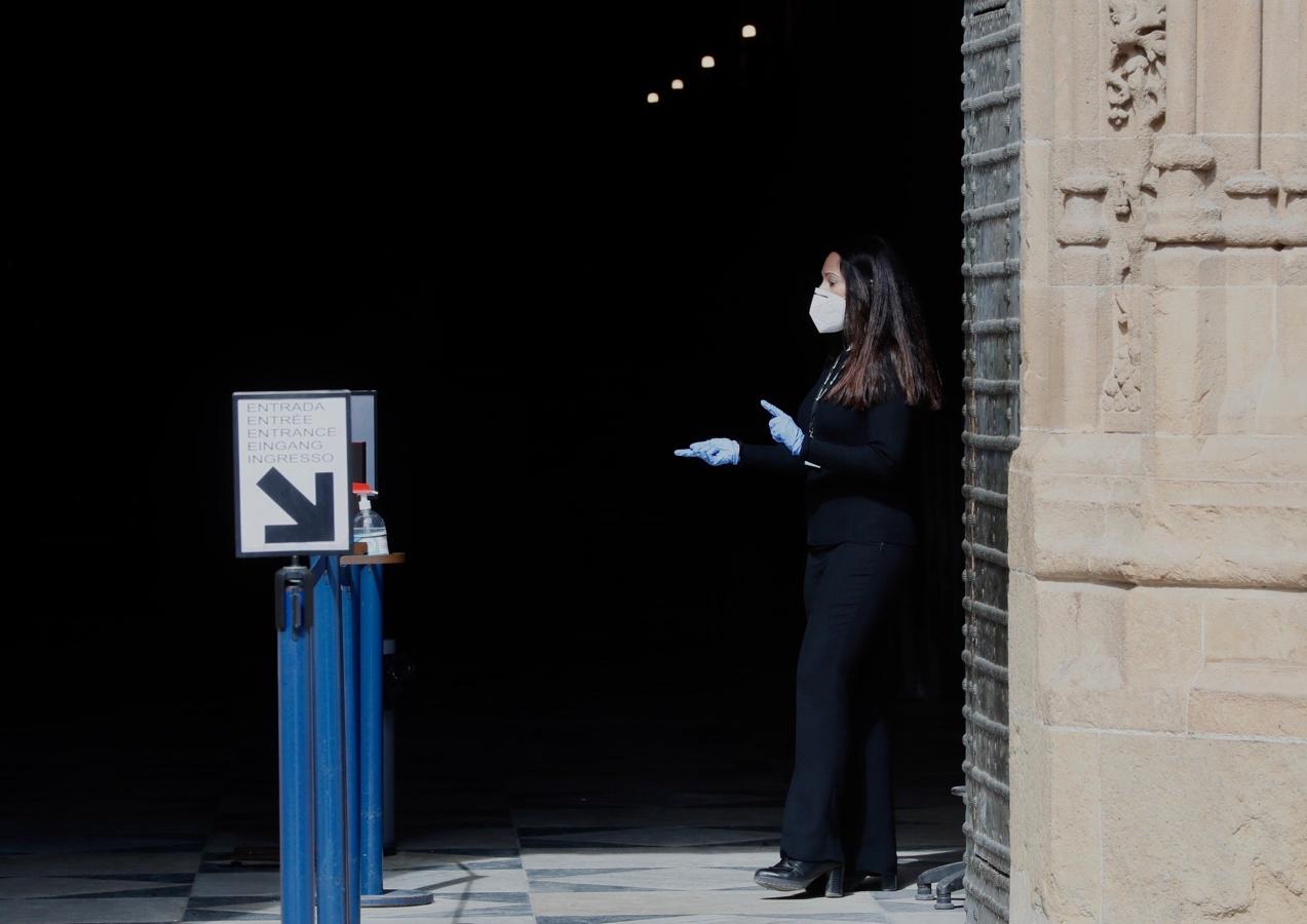 Control del aforo. Una persona controla a las puertas de la Catedral de Sevilla que no se sobrepase el 30% de los asistentes a la seo, junto a unos tornos preparados que no ha hecho falta utilizar