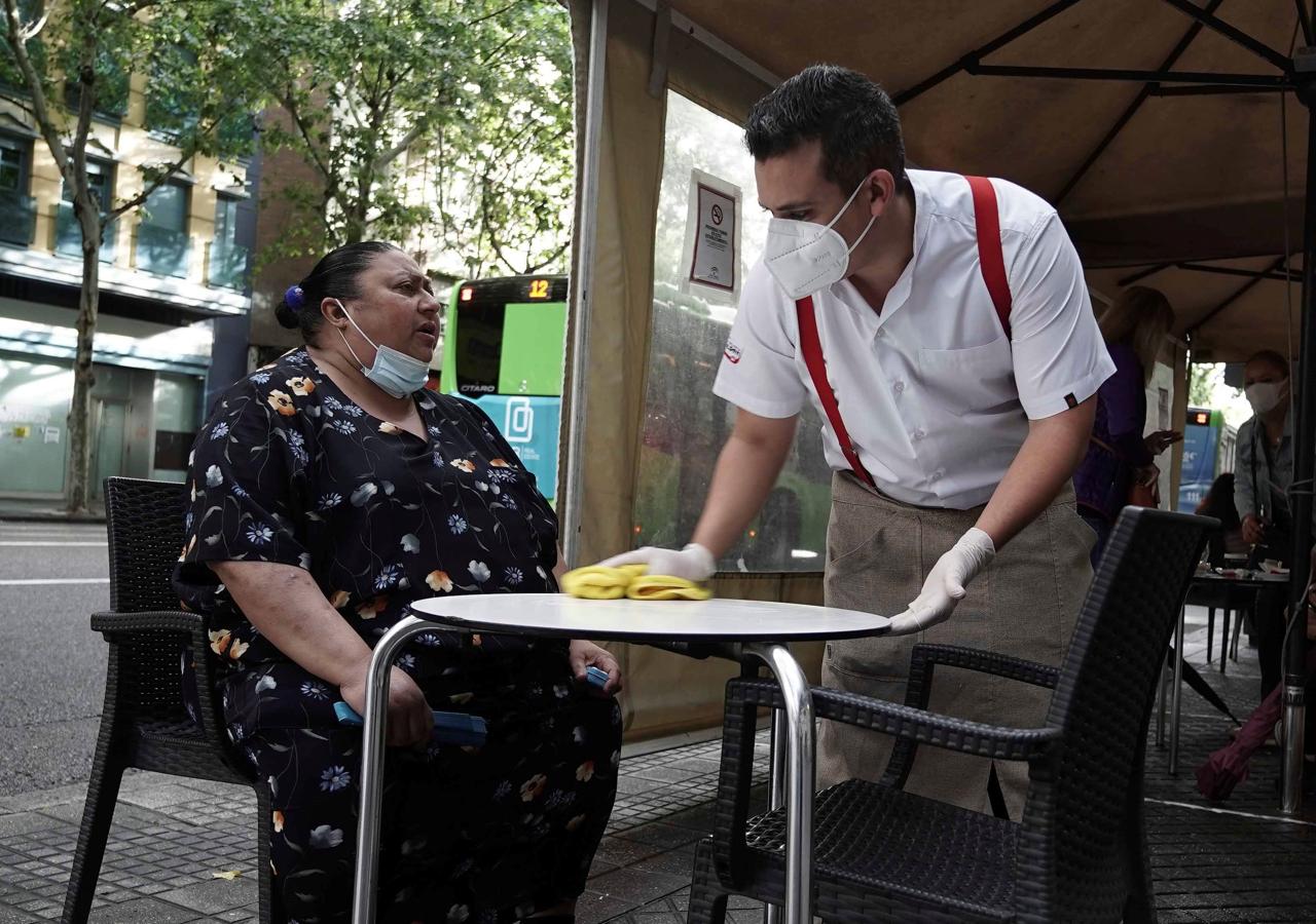 Limpieza extrema en las cafeterías. Una mujer espera ser atendida en una establecimiento del centro de Córdoba, mientras el camarero, provisto de guantes y mascarilla, limpia escrupulosamenrte la mesa