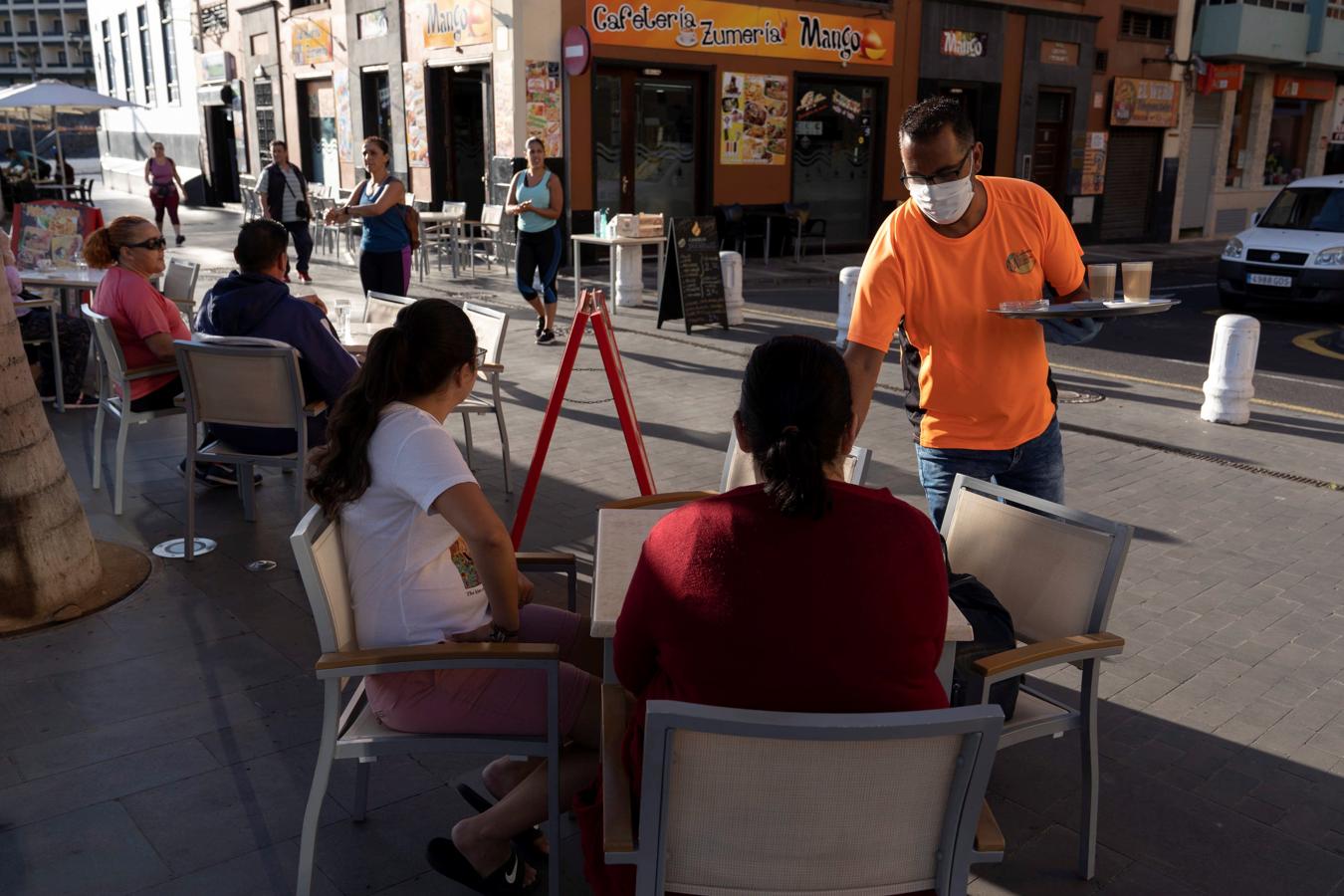 En fila para conseguir una mesa libre. En el Puerto de la Cruz (Tenerife), dos mujeres hacen cola a la espera de que una de las mesas del establecimiento se quede libre. La limitación de los veladores al 50% va a convertir en habitual escenas como esta