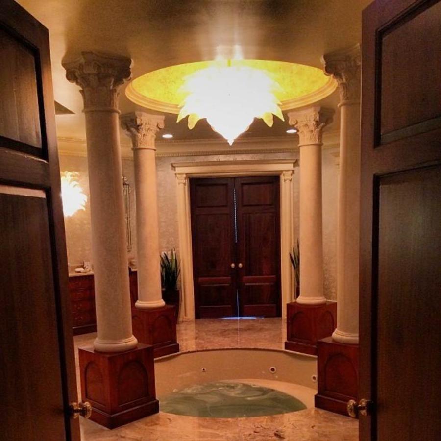 Baños a todo lujo. La mansión cuenta con 8 dormitorios y 12 baños, y aunque estamos seguros de que no todos serán tan fastuosos, seguramente sigan la misma línea. En este concretamente el jacuzzi situado en el centro y las columnas recuerdan a las termas grecorromanas, un lujo al alcance de unos pocos.