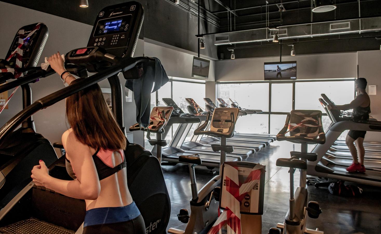 De vuelta a los gimnasios. Los gimnasios abren sus puertas también en la fase 3, como en este de Sevilla. Las medidas de seguridad son estrictas, como se puede comprobar en la imagen, donde una joven limpia uno de los aparatos tras ser usado