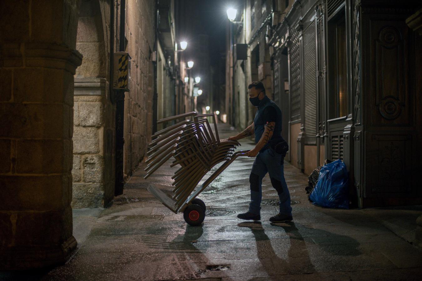 Orense se prepara para el cierre. Un trabajador retira las sillas de la terraza de la Plaza Mayor de la ciudad para cumplir con el toque de queda que conlleva el cerrojazo a los locales de restauración y al ocio nocturno de once de la noche a seis de la mañana, con carácter general, con las matizaciones que establezcan los distintos gobiernos regionales que pueden adelantar o retrasar una hora