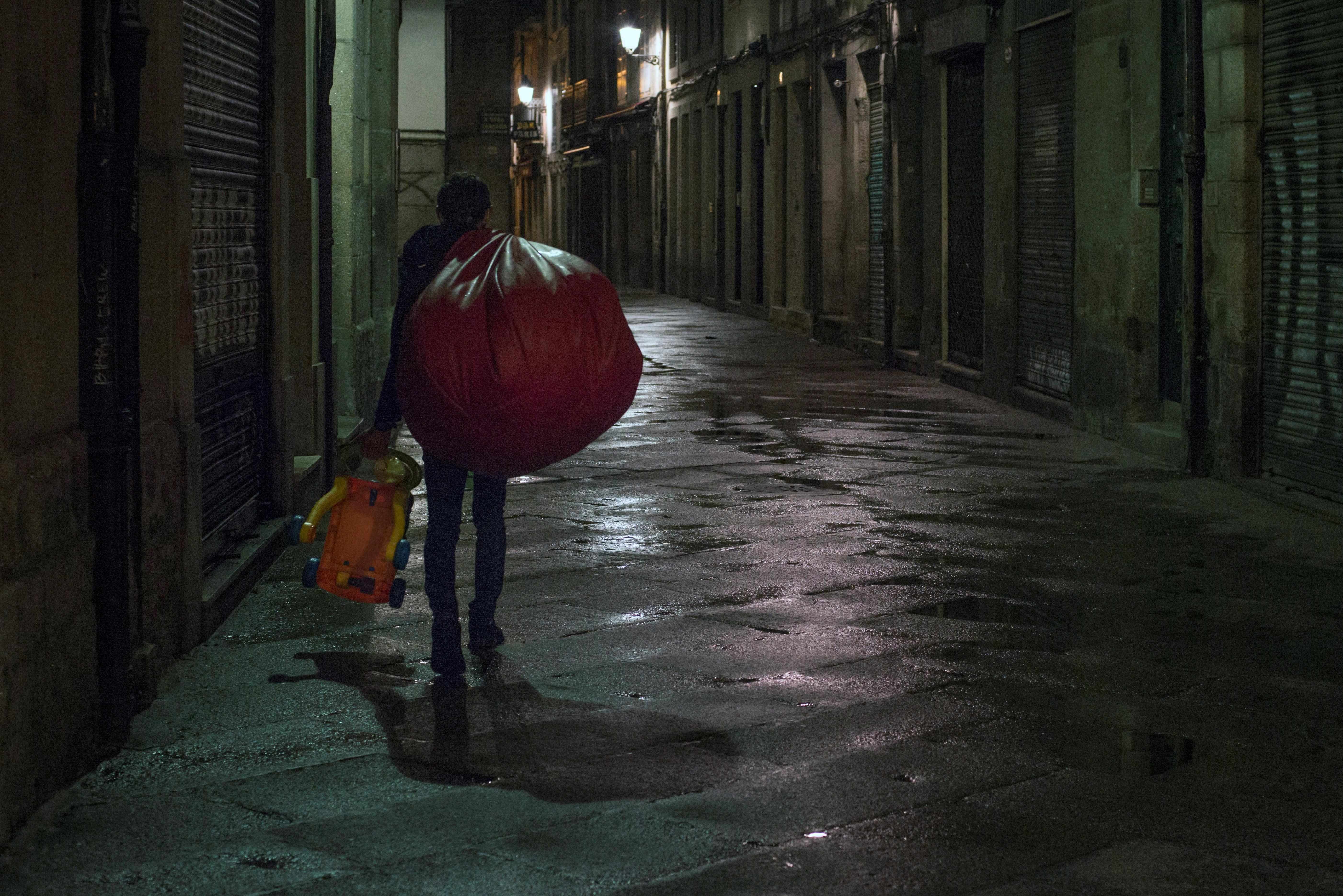 Adiós a la venta ambulante ilegal. Un hombre, con todos sus bártulos a cuestas, regresa a su casa por el toque de queda. Carga un abultado paquete y el juguete de un niño en Orense. El «top manta» ilegal que burla la vigilancia policial ahora lo tiene más difícil por la restricción de la movilidad