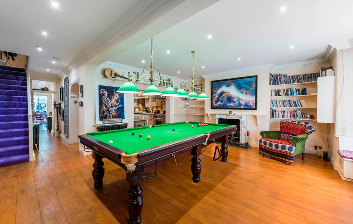 Así es el adosado de Ronnie Wood. Otro de las espacios que más llama la atención es una sala de entretenimiento que recrea las salas de billar con accesorios de iluminación tradicionales de este tipo de clubs, además de, por supuesto, una magnífica mesa de billar. Al fondo se pueden ver unas escaleras con moqueta morada que contrasta con dicha estancia.