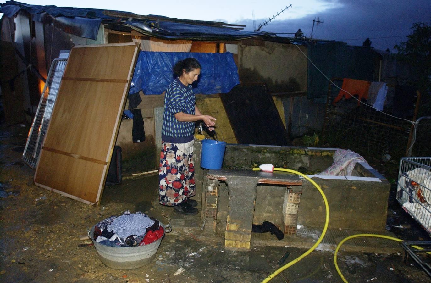 Una vecina recoge agua de la única fuente con la que contaban los vecinos en el año 2003