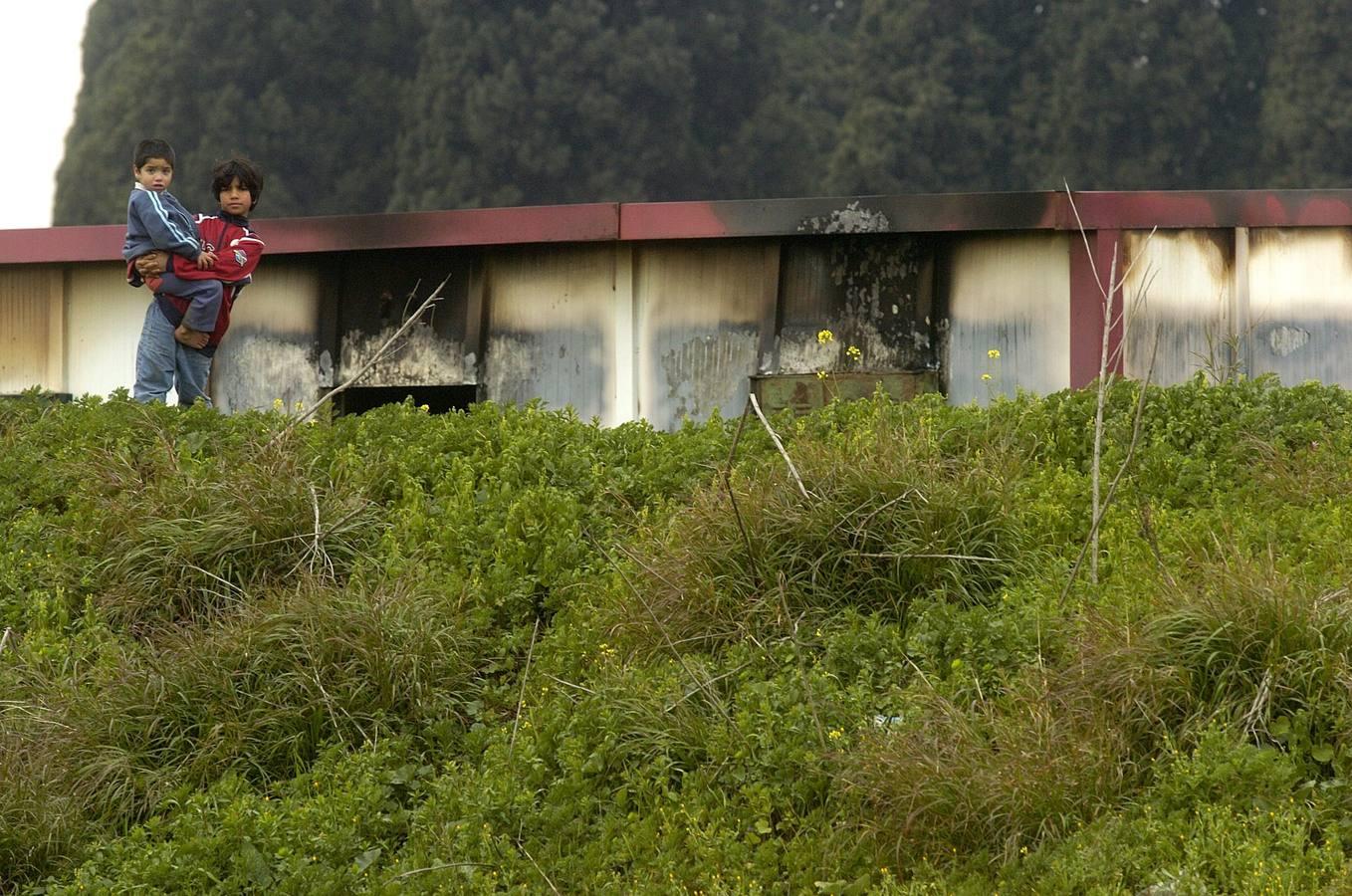 Dos niños vigilan a un fotoperiodista de ABC ante dos casas prefabricadas afectadas por un incendio