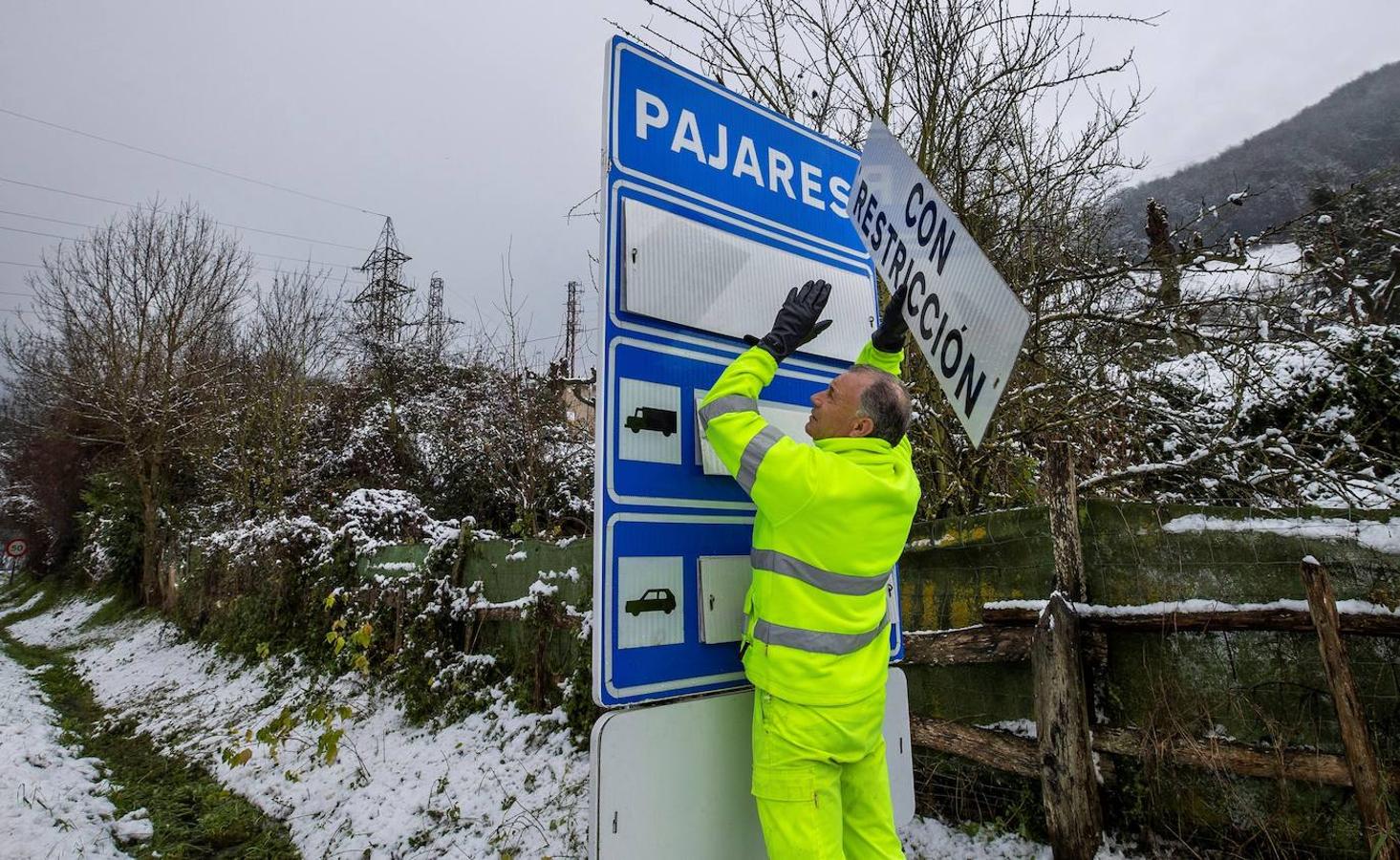 La autopista del Huerna (AP-66), principal vía de comunicación entre Asturias y León, está ya reabierta al tránsito de camiones tras las intensas nevadas de las últimas horas. En la imagen un operario cambia un cartel del estado del puerto de Pajares, en el que se prohíbe la circulación de vehículos articulados, camiones y autobuses. 