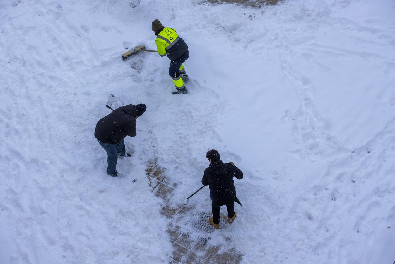 Varias personas tratan de abri un camino entre la nieve e la ciudad de Ávila