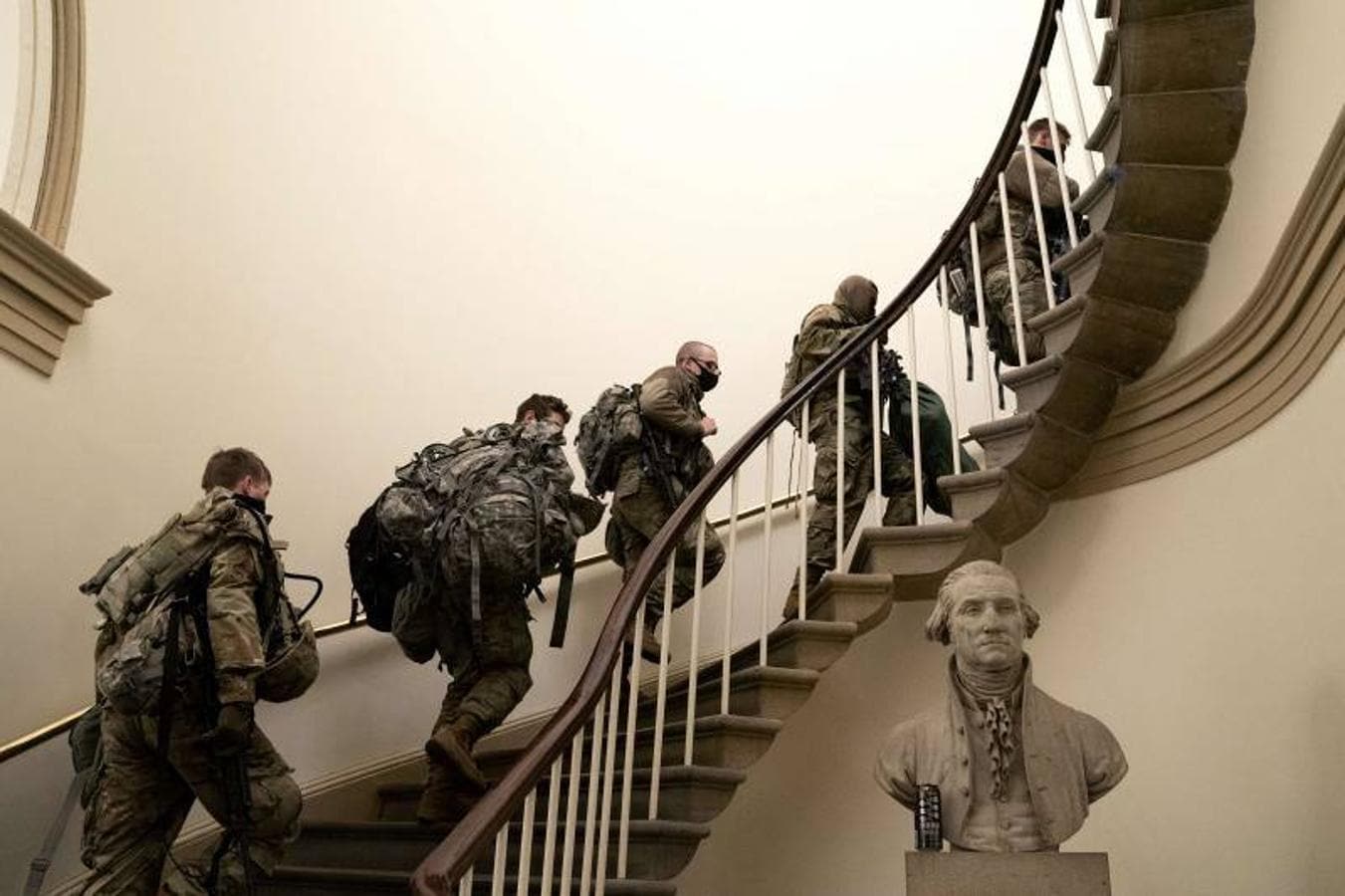 Guardias protegidos con mascarillas suben unas escaleras en el Capitolio.. 