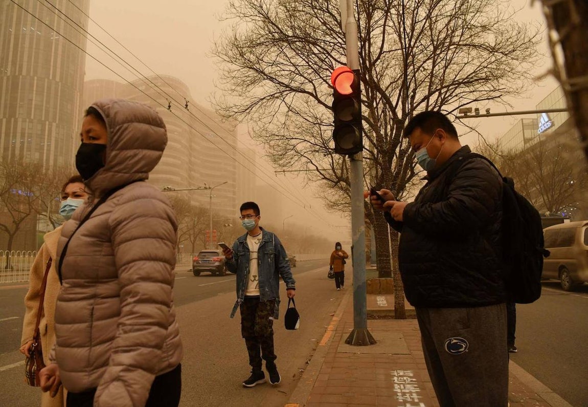 Un grupo de personas aguarda para cruzar la calle durante la tormenta de arena. 