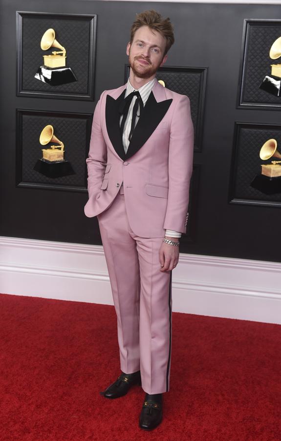 Finneas - Alfombra roja de los Grammy 2021. Gucci de nuevo volvió a estar presente con un llamativo conjunto, un traje rosa empolvado de aires setenteros que incluía detalles en negro en solapas y pantalón. Lo complementó con una camisa de rayas y un lazo de terciopelo.
