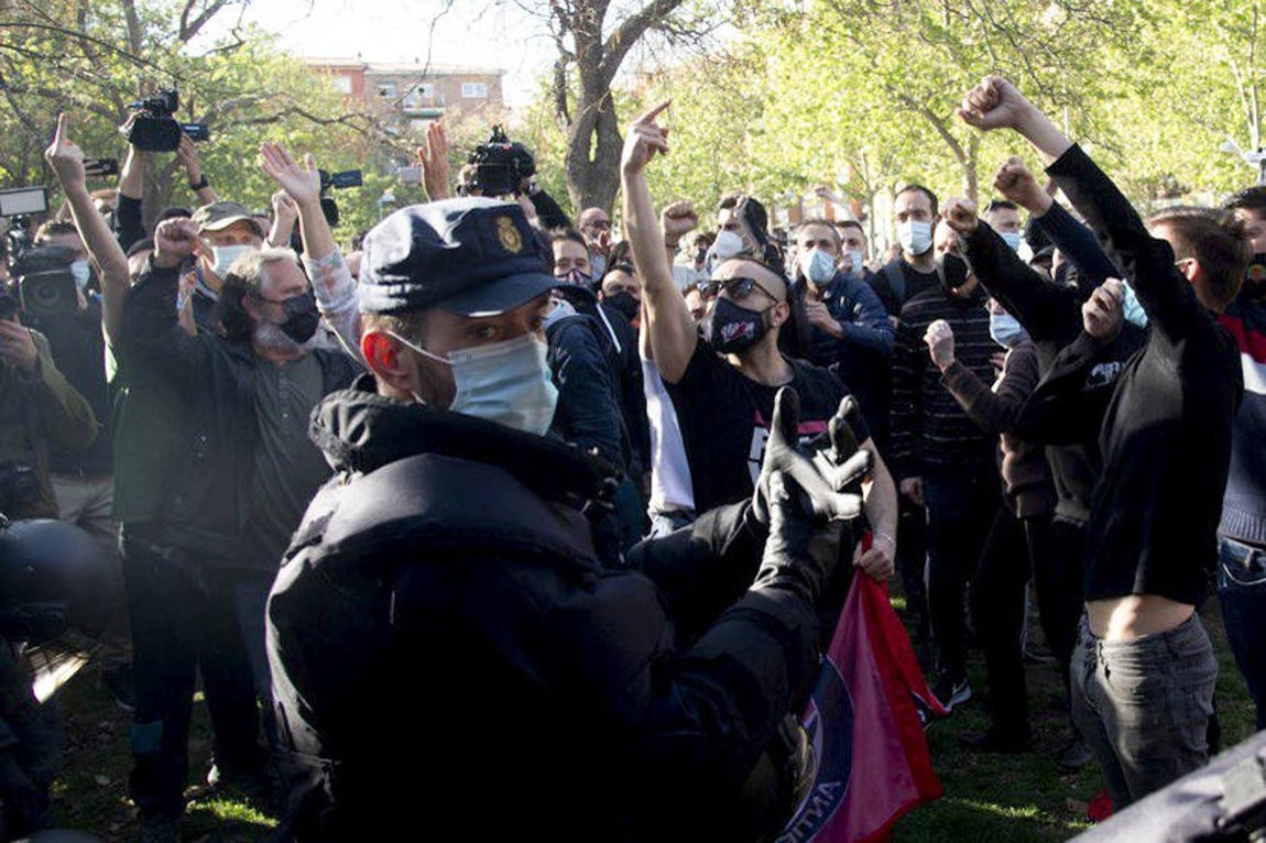 Varios manifestantes gritan junto a un agente de la Policía Nacional (c). 