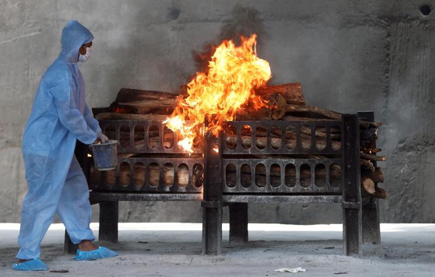 Un trabajador rocía un líquido inflamable en la pira funeraria en llamas de un hombre que murió por el coronavirus, en un crematorio a las afueras de Bombay el 15 de abril. 