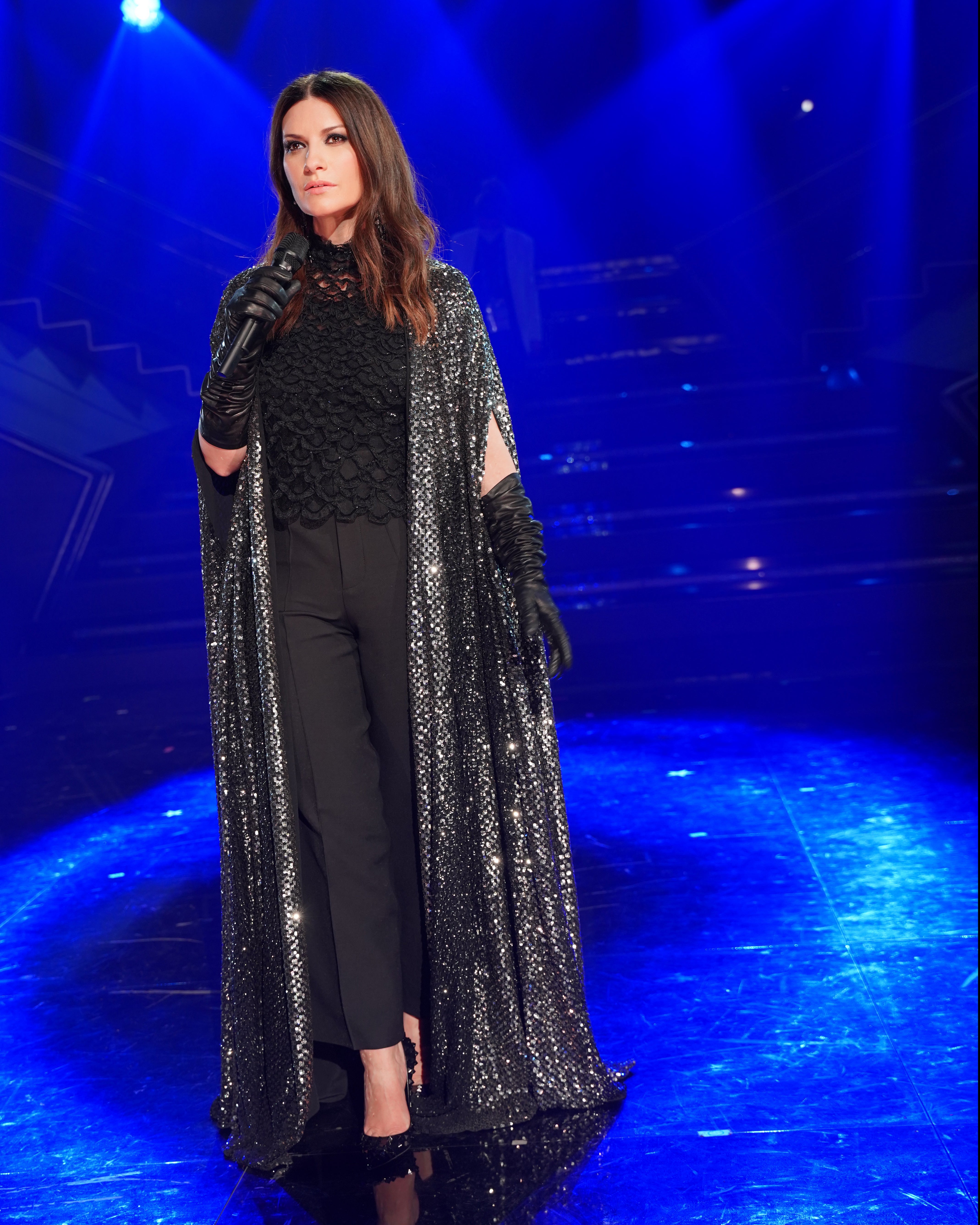 La cantante italiana apuesta con frecuencia por el negro, elegante y siempre certero. En el festival de San Remo escogió un conjunto de Valentino formado por pantalones, top bordado y capa con brillos.. 