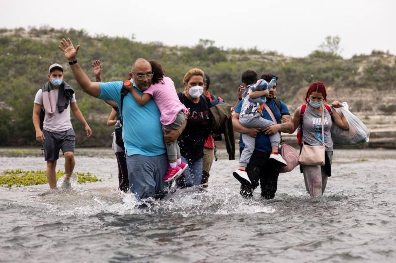 Con los niños en brazos y cargados con sus pertenencias, el grupo intenta cruzar el río. 