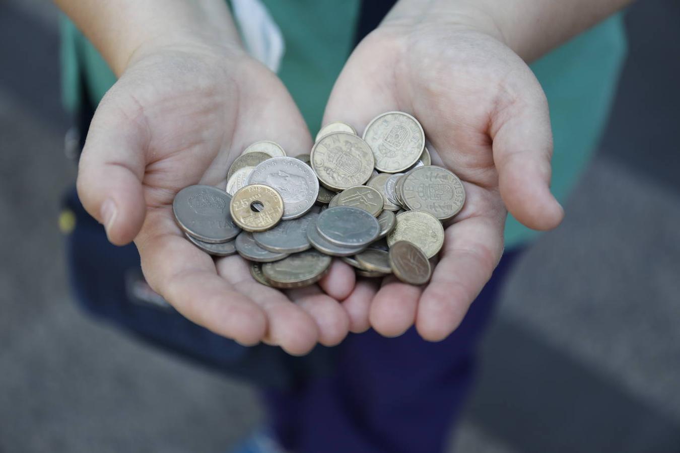 Colas de españoles con monedas de pesetas. 