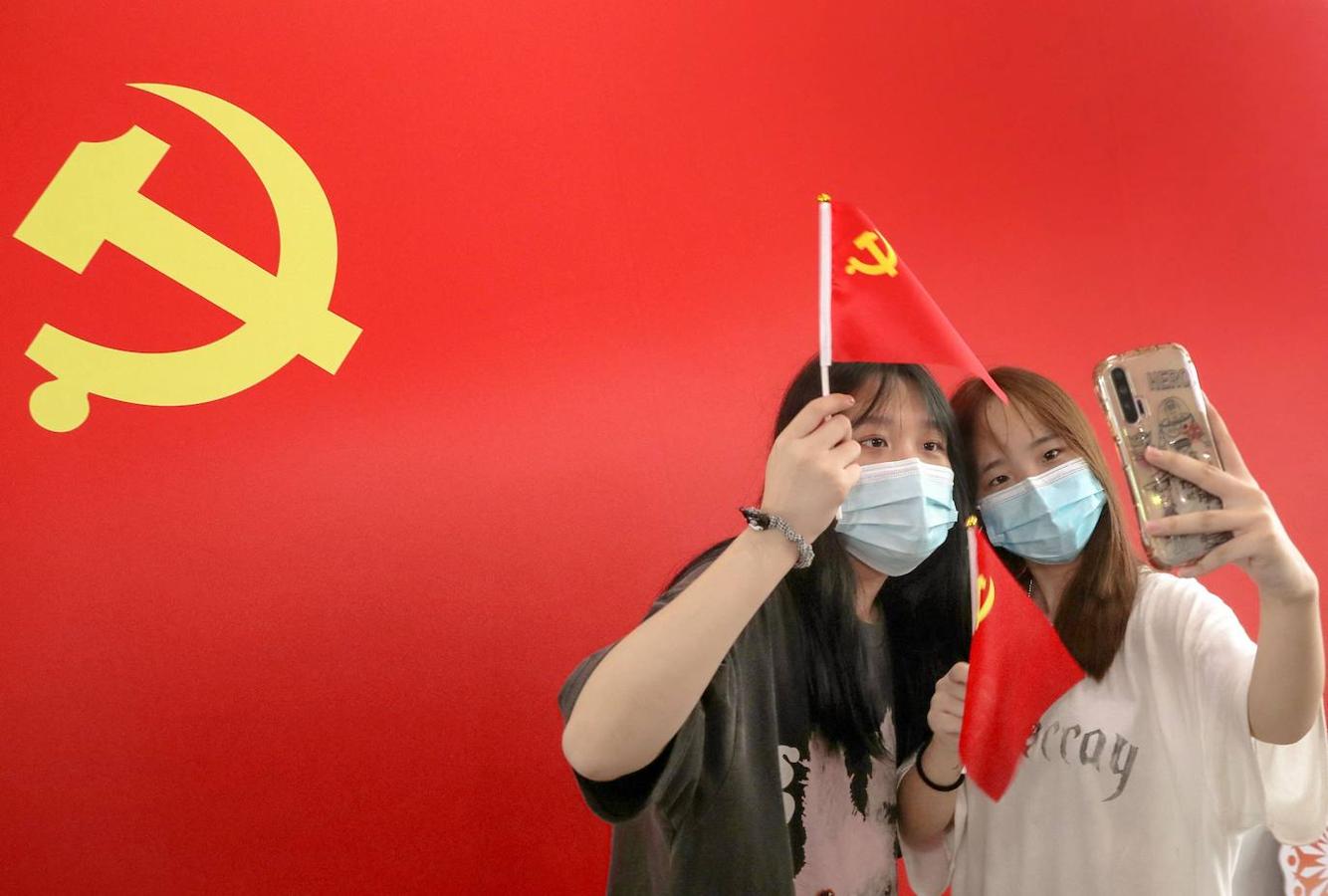 Dos jóvenes se fotografían con una bandera del Partido Comunista de China en la estación de tren de Nantong durante las celebraciones para conmemorar su centenario. 