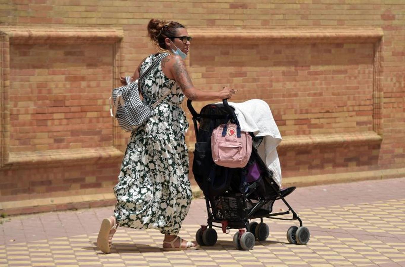 Una mujer intenta proteger del Sol a su bebé con una tela (Sevilla). 