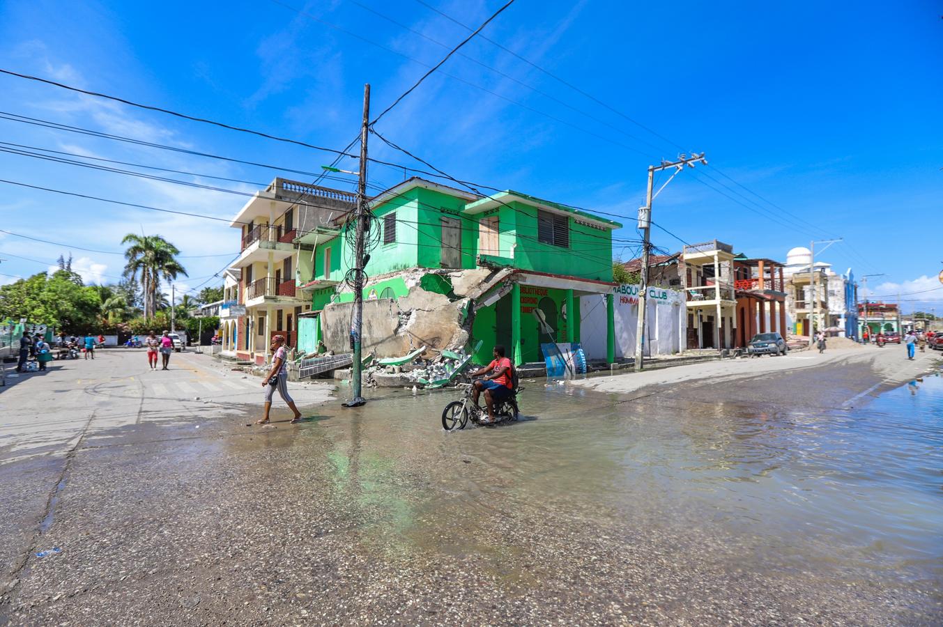 Grupos de personas transitan por una calle inundada tras el seísmo de 7,2 grados en Los Cayos. 