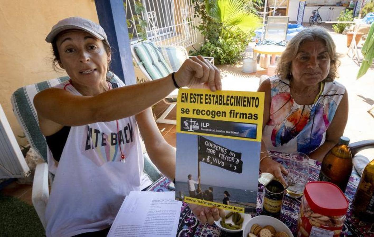 Paula Valdivieso muestra la campaña de recogida de firmas para una Iniciativa Legislativa Popular junto a otros residentes en la zona. 