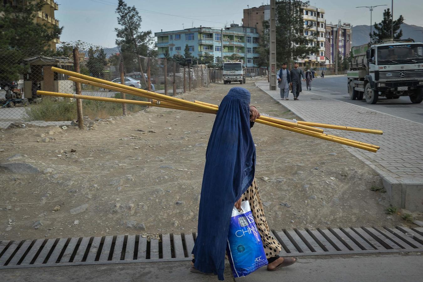 Una mujer afgana vestida con burka camina por un sendero en Kabul. 