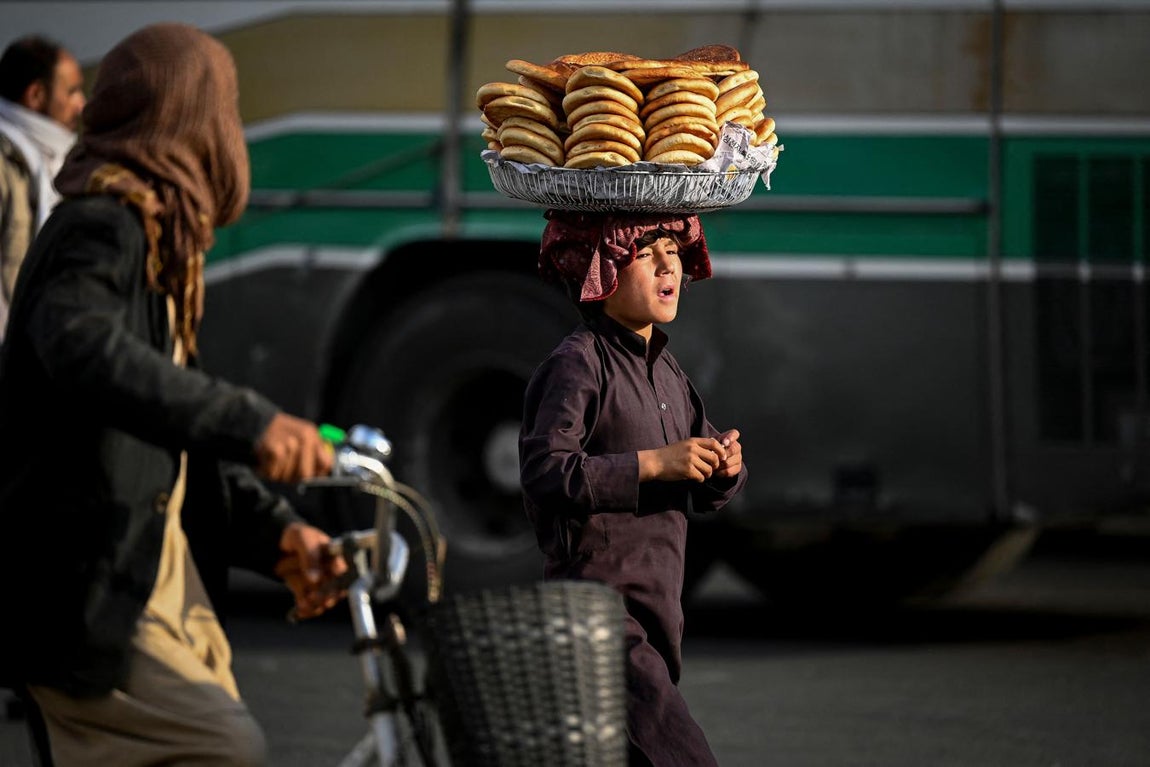 Un niño lleva hogazas de pan en la cabeza mientras camina por una calle en Kabul. 