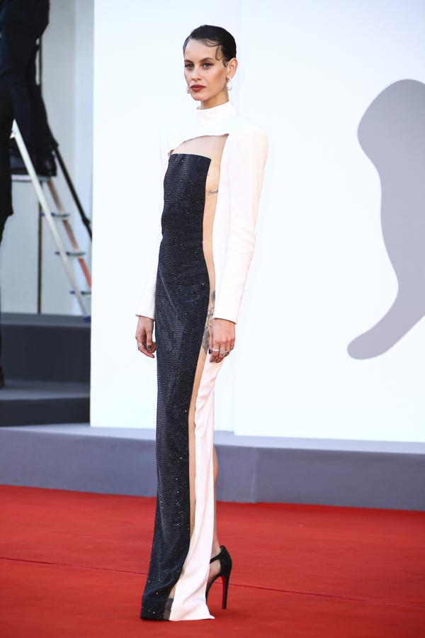 Milena Smit, en el Festival de cine de Venecia 2021. Con vestido estructurado también en blanco y negro y con transparencias de Balmain. Sandalias de pailletes negros de Mascaró, anillos en oro blanco y diamantes y pendientes de la colección Serpenti Seduttori de Bvlgari, completaron el estilismo a la perfección.