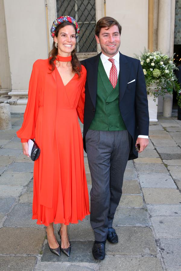 Marie-Astrid de Liechtenstein y Ralph Worthington - Look de día. Muiy discreta y elegabnte con un vestido midi anaranjado con mucho vuelo que conjuntó con unos stilettos metalizados y diadema de flores.