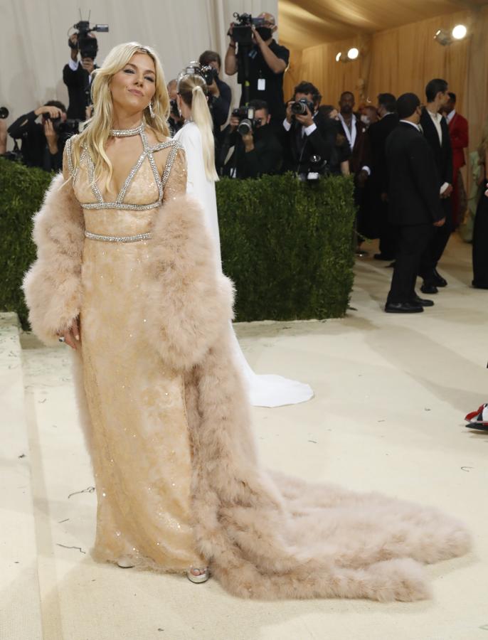 Sienna Miller- Alfombra roja de la Gala MET 2021. De Gucci con un vestido inspirado en los años veinte. Un diseño beige repleto de paillettes con predrería bordada eel escote y una estola de pelo rematand el look.