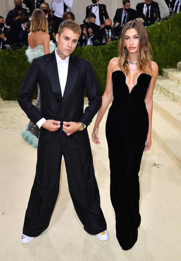 Justin y Hailey Bieber - Alfombra roja de la Gala MET 2021. La modelo marcó curvas con un vestido negro ajustado de escote corazón de Saint Laurent que contrastaba con el traje oversize de Balenciaga de su marido Justin.