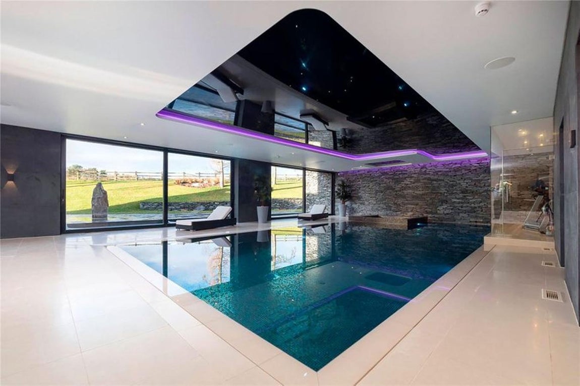 La nueva mansión de Cristiano en Mánchester. El punto clave de la casa es la zona de aguas, con una gran piscina y jacuzzi que comunican con el salón y el jardín. El aspecto futurista de la misma se ve acrecentado con las luces de neón púrpura y el gran espejo en el techo. No faltan las hamacas para relajarse.